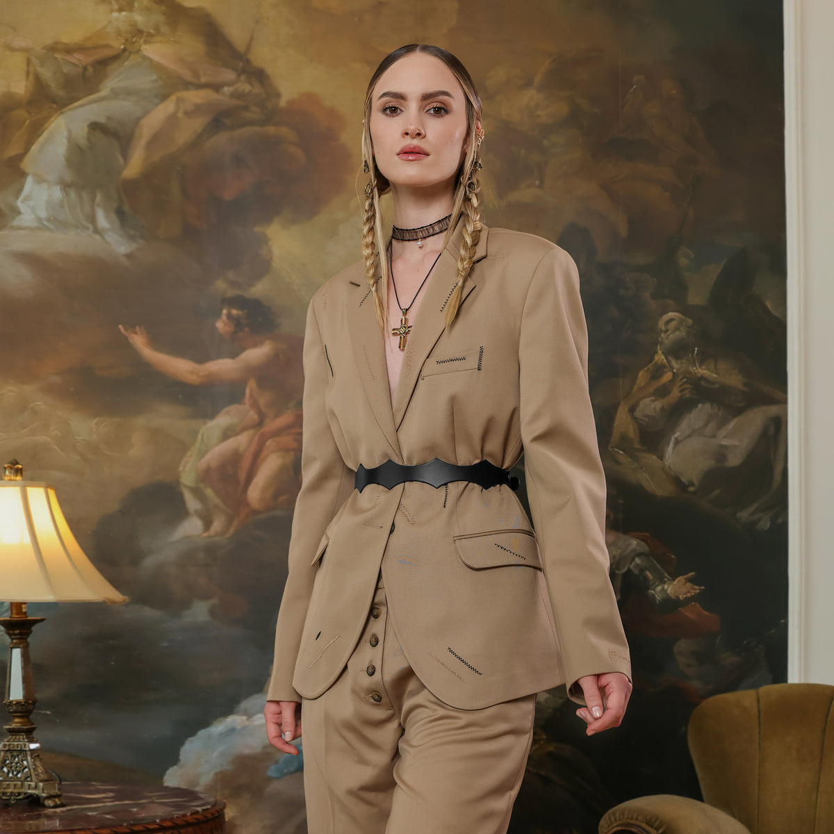 Woman in a beige suit standing in front of a classical painting