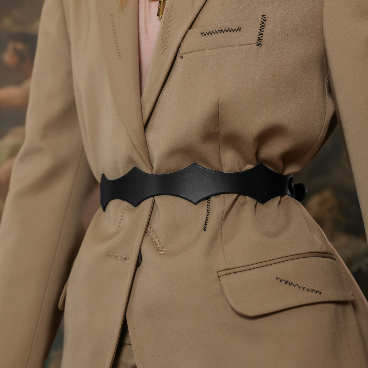Close-up of a beige suit with a black belt