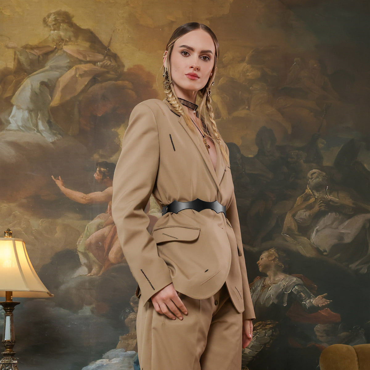 Woman in a beige suit standing in front of a classical painting