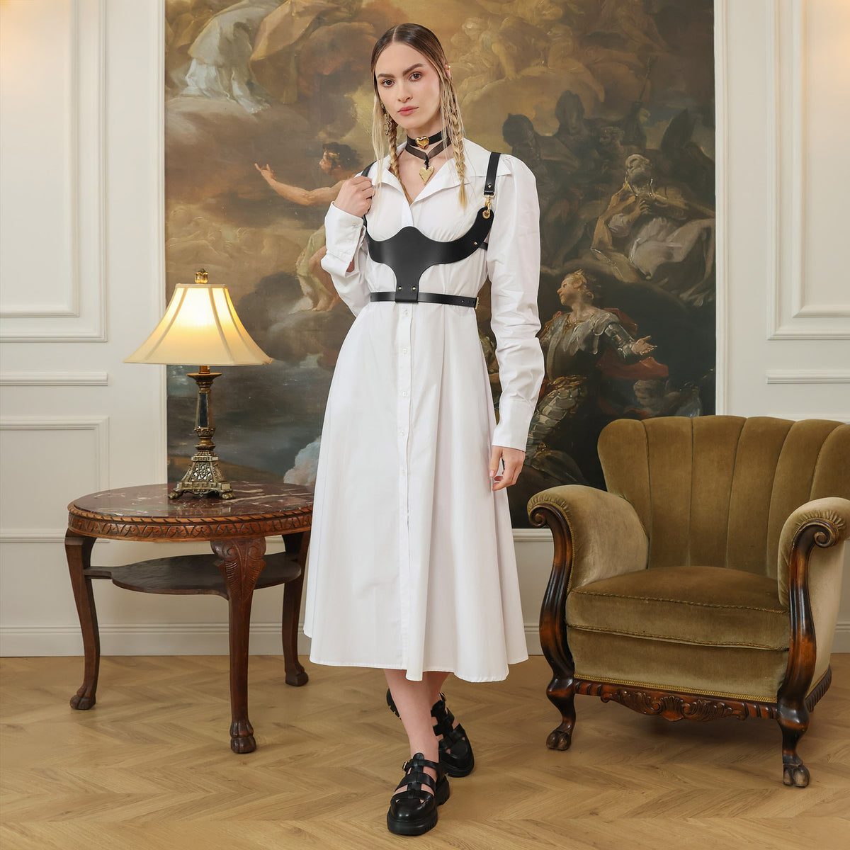 Woman in a white dress with black harness standing in front of a classical painting