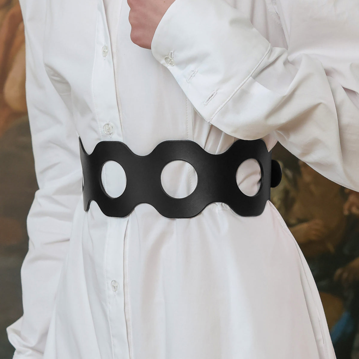Person wearing a black belt with three circular holes on a blurred background