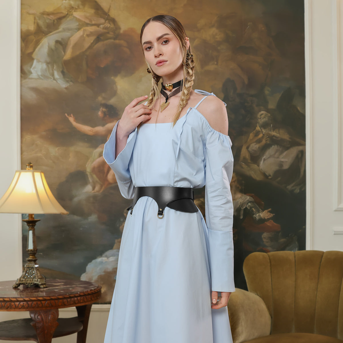 Woman in a light blue dress standing in a room with a large painting in the background