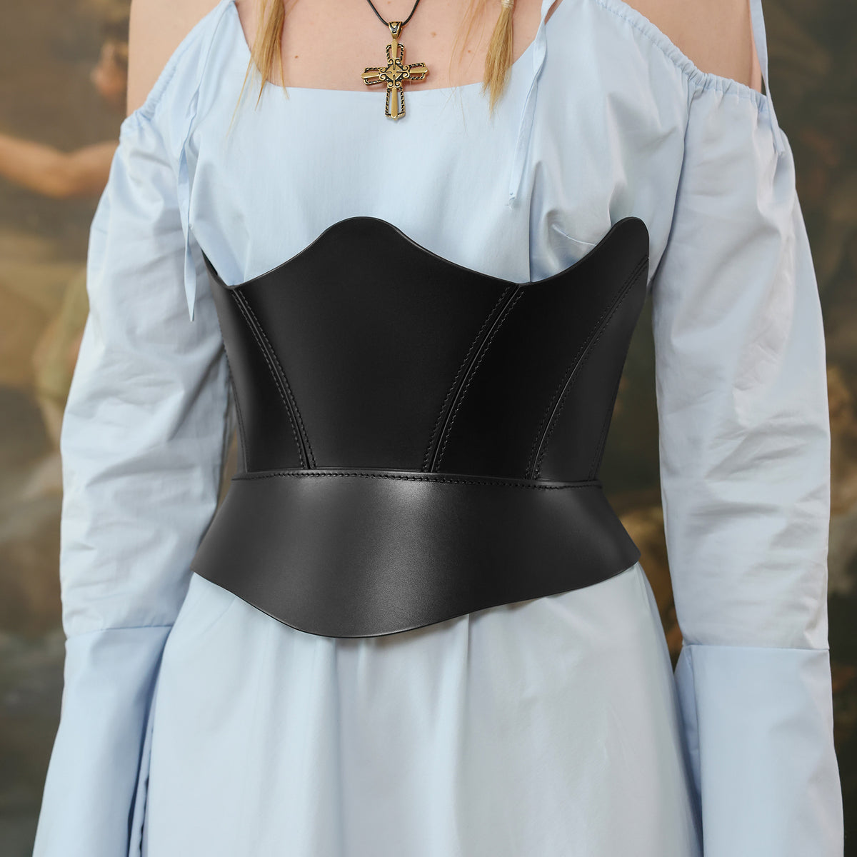 Person wearing a black leather corset over a light blue off-shoulder top.