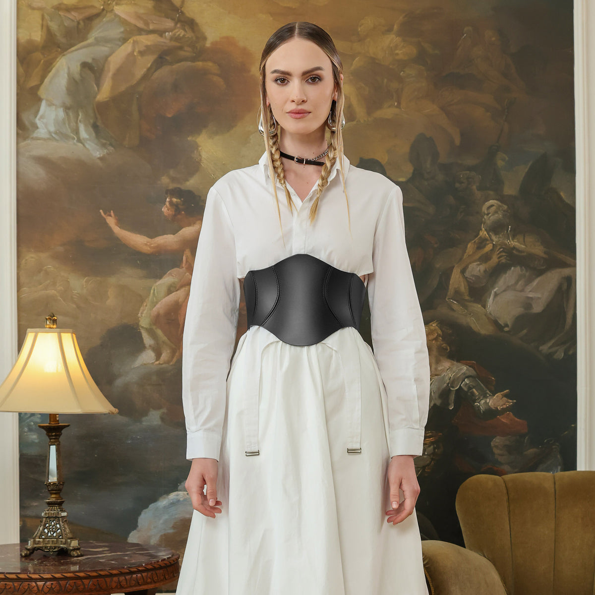 Woman wearing a white blouse and black corset in front of an ornate painting