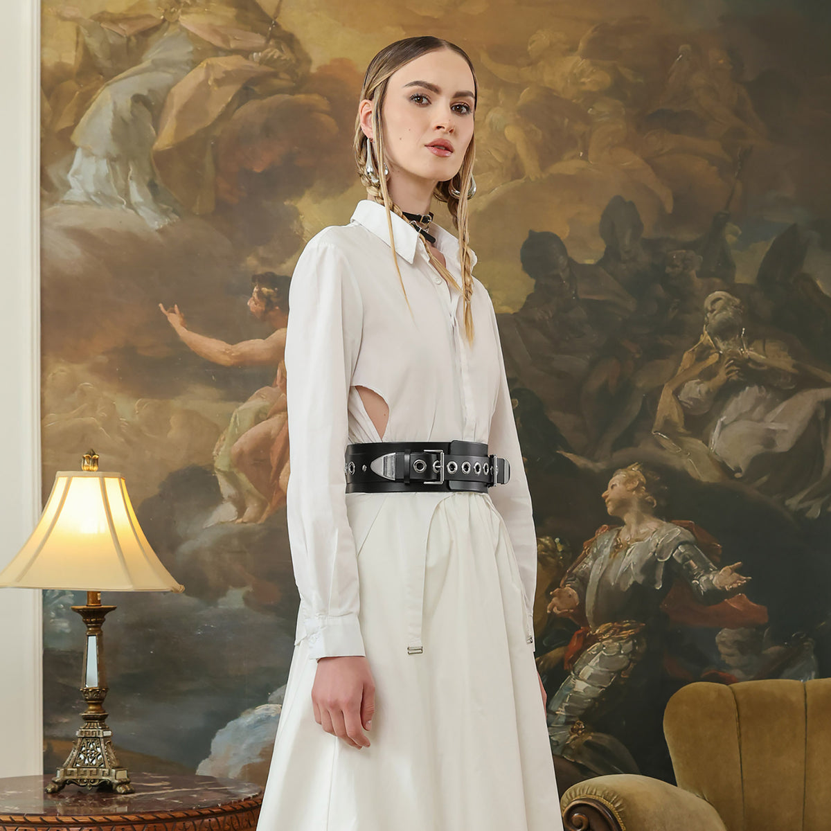 Woman in a white dress standing in front of a classical painting