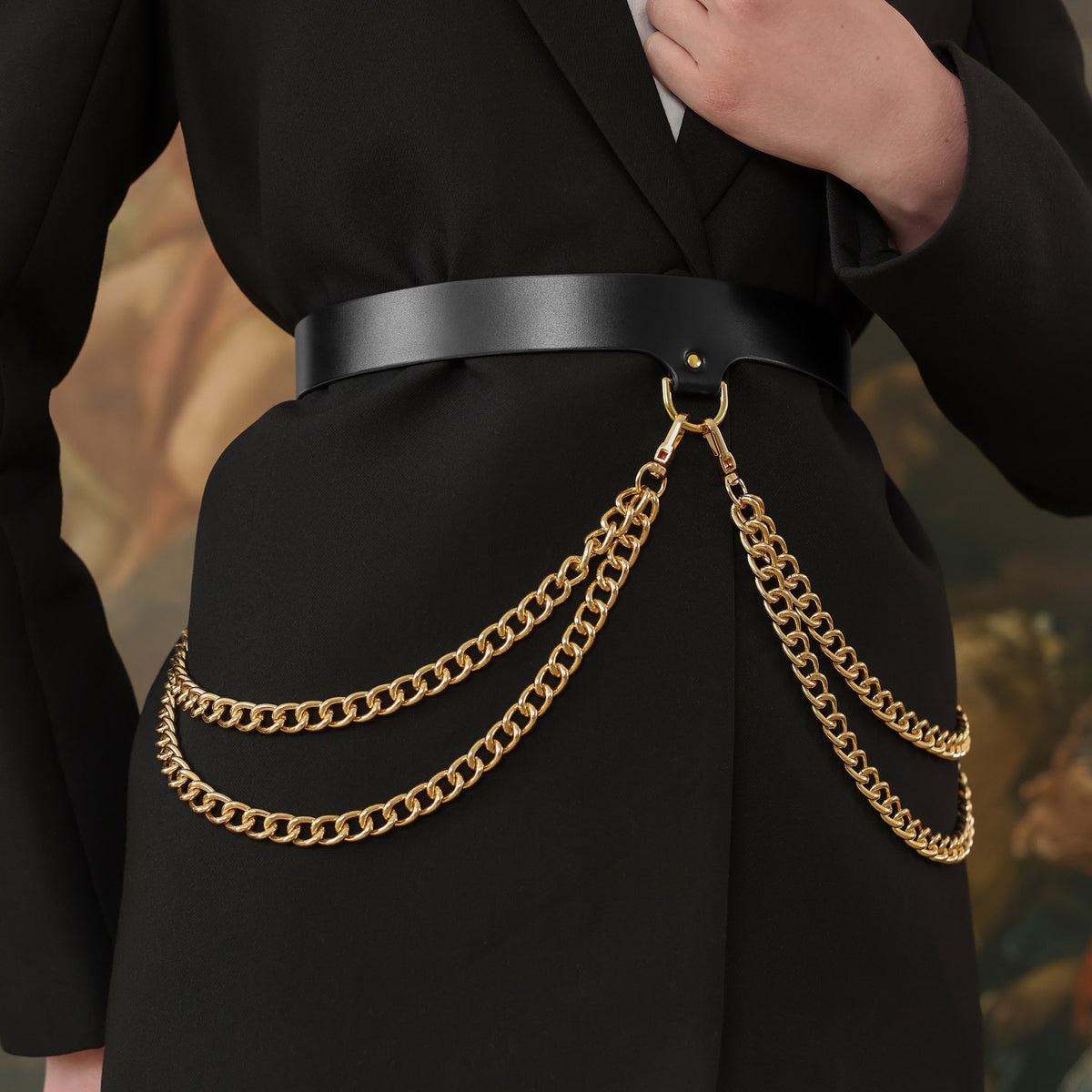 Black coat with a gold chain belt against a blurred background