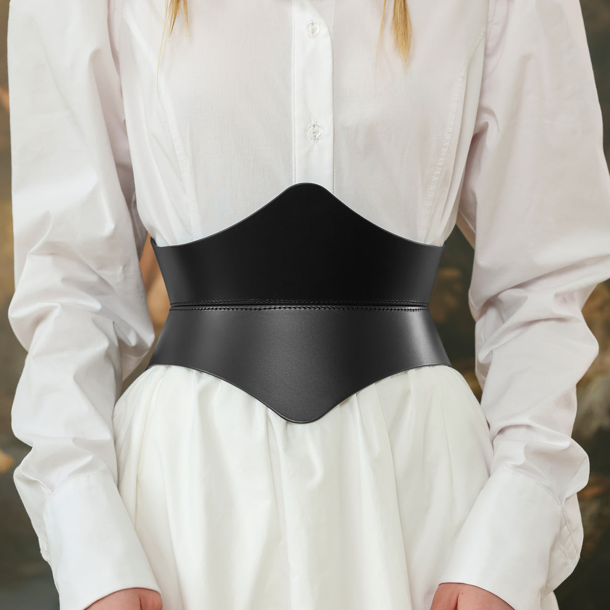 Person wearing a black belt over a white shirt with a blurred background