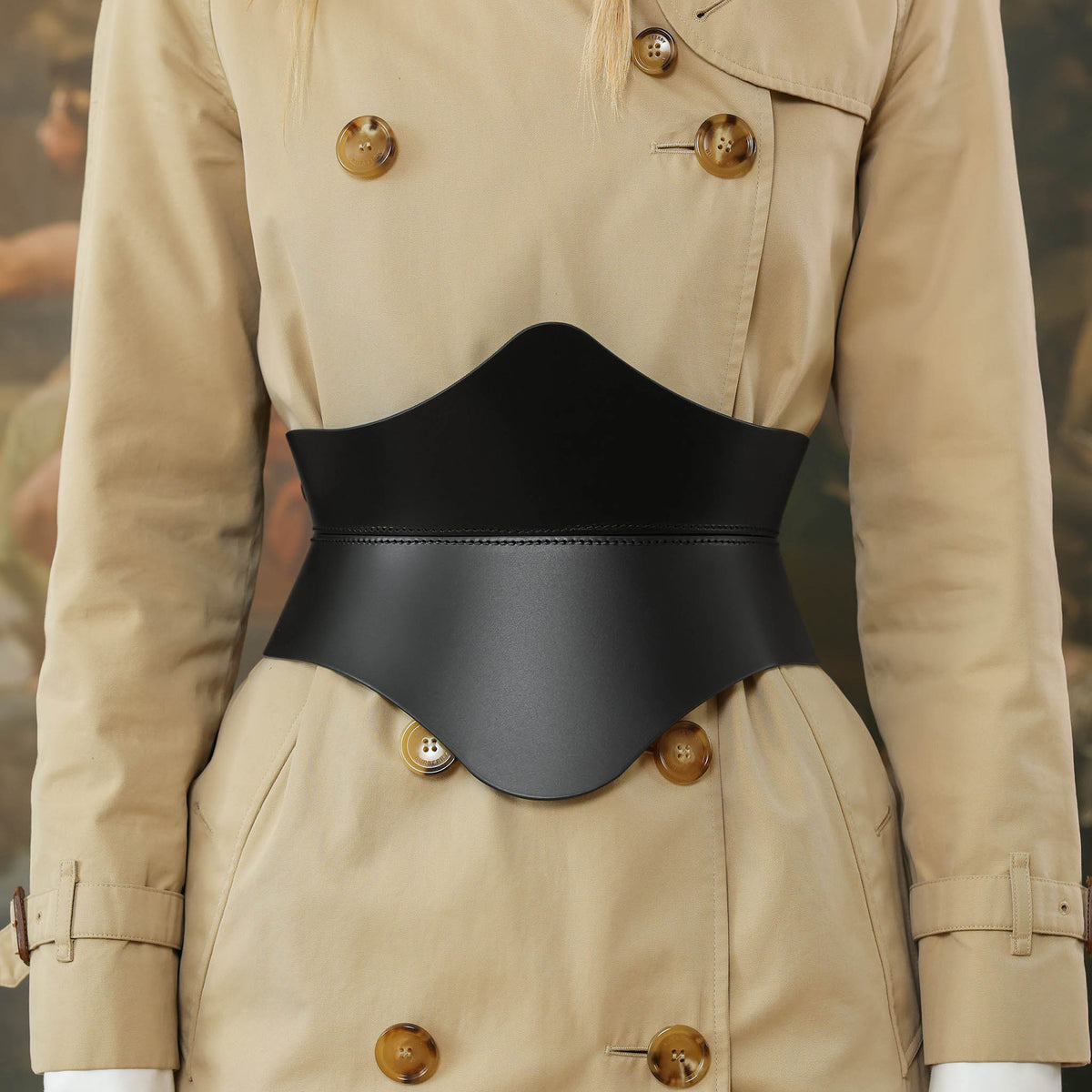 Person wearing a beige trench coat with a black belt over a blurred background