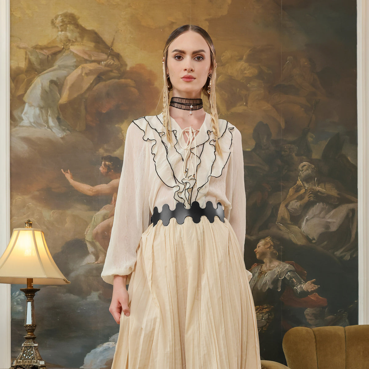 Woman in a stylish outfit standing in front of an classical painting