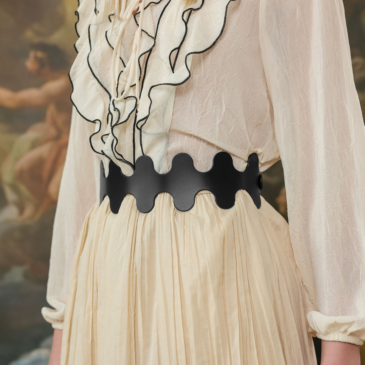 Black belt with unique design worn by a person in a light-colored outfit.