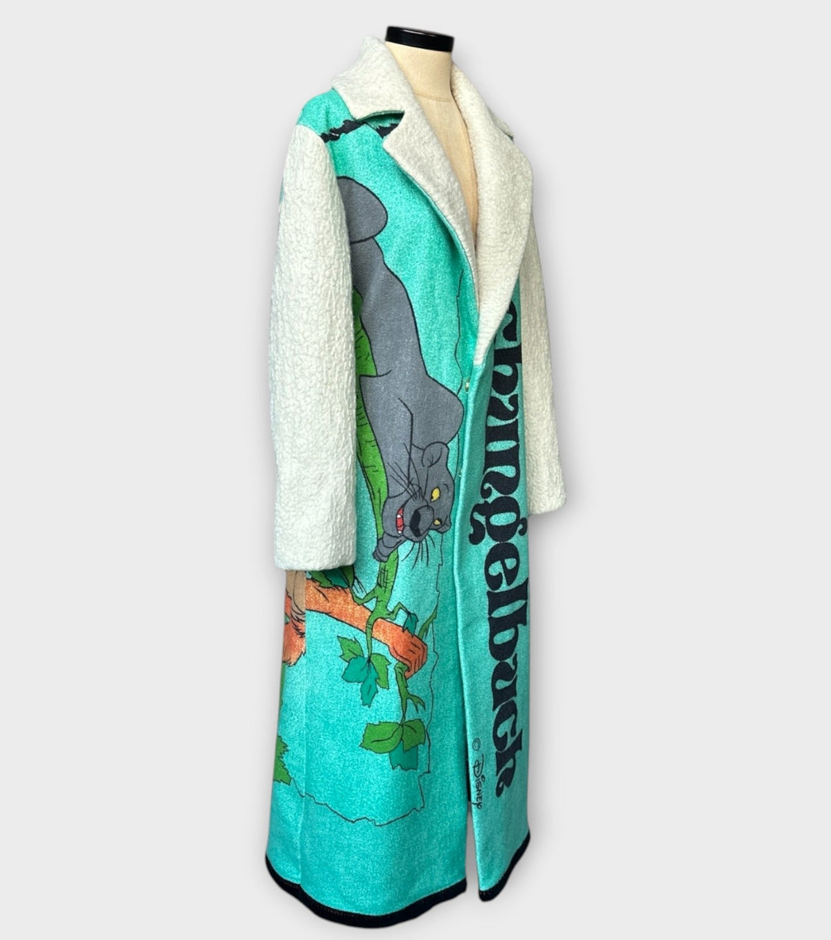 STUDIO WUNDERBAR Jungle Book Coat: turquoise graphic long coat with a Bagheera panther illustration from The Jungle Book and cream sleeves, upcycled one-of-a-kind coat, alternate angle, buy at DOORS NYC