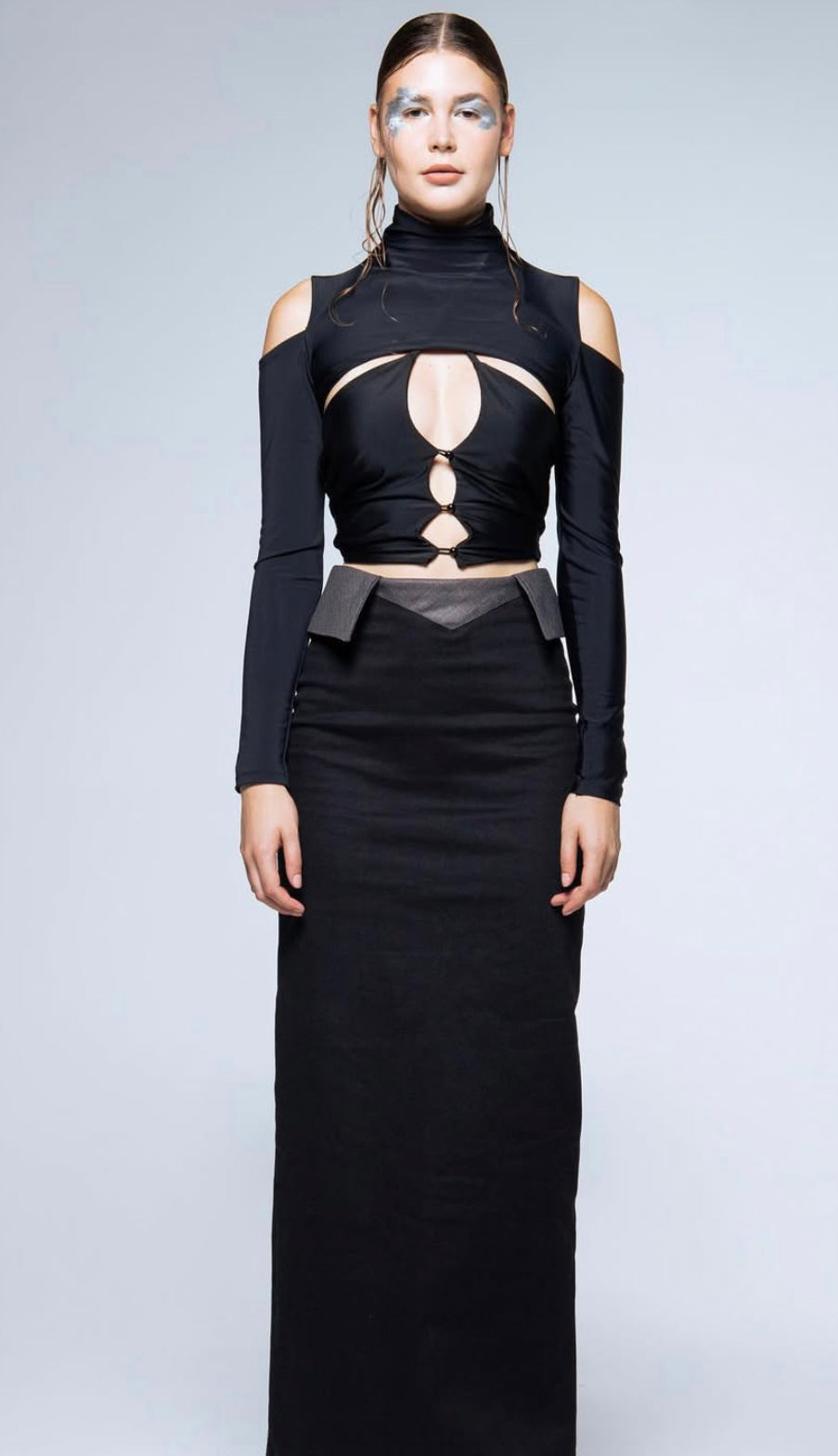 Black sleeveless top with cut-out design and long black skirt on a plain background
