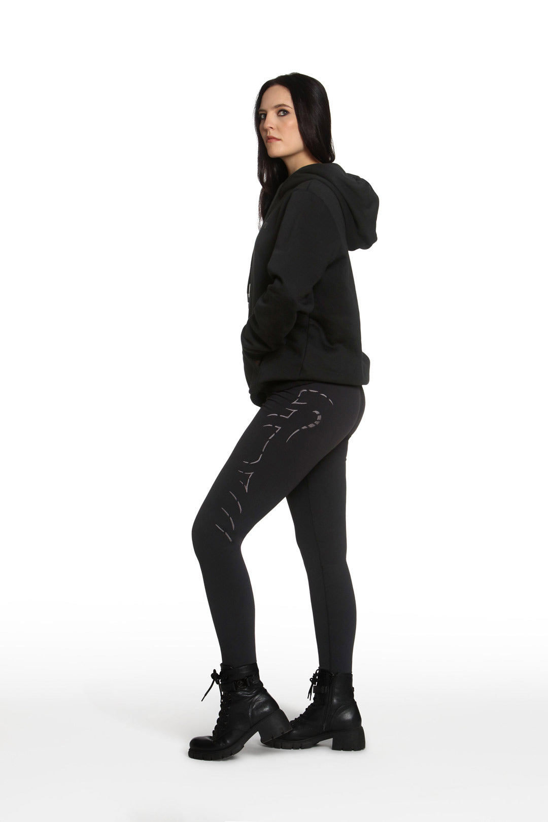 Woman wearing a black hoodie, leggings, and boots on a white background