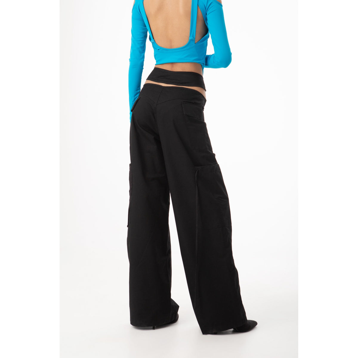 Person wearing a blue top and black wide-leg pants on a white background