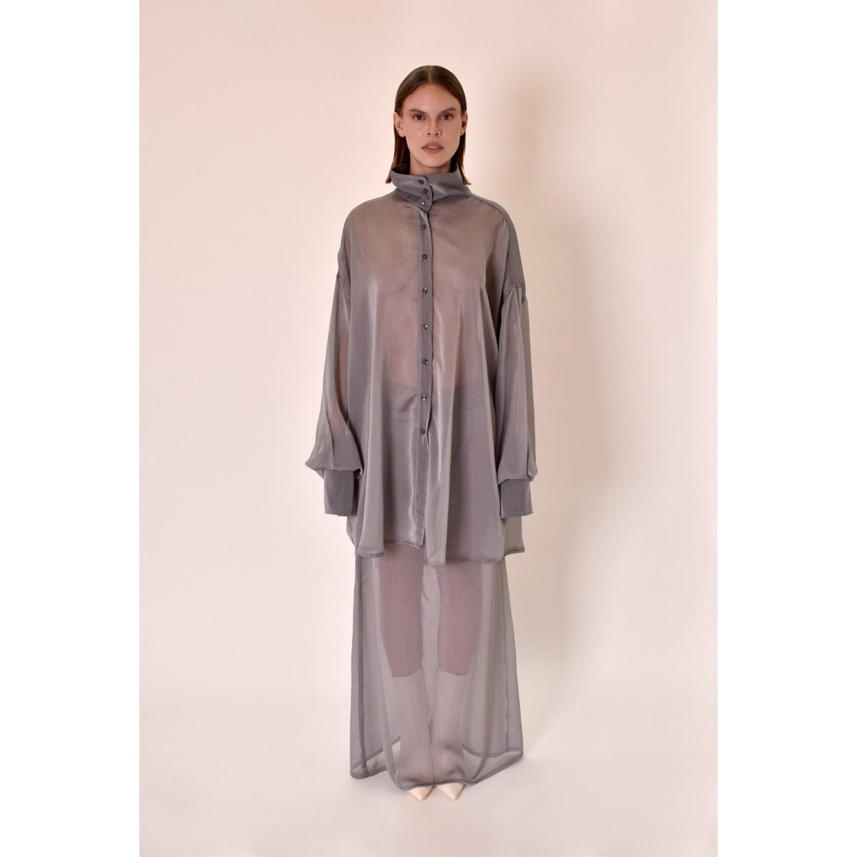 Woman wearing a silver outfit with sheer elements on a beige background