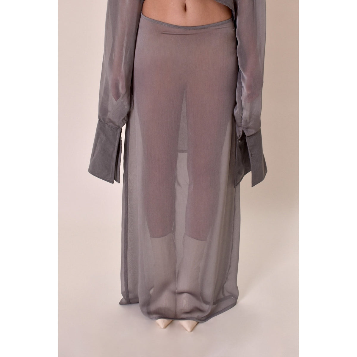Sheer silver skirt with a matching top on a neutral background