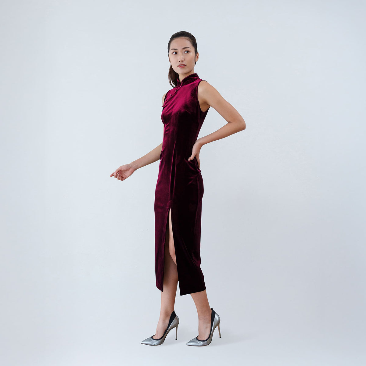 Qipology crimson red velvet sleeveless qipao dress with Mandarin collar, beaded detail and front slit, worn by model, look 2, buy at DOORS NYC