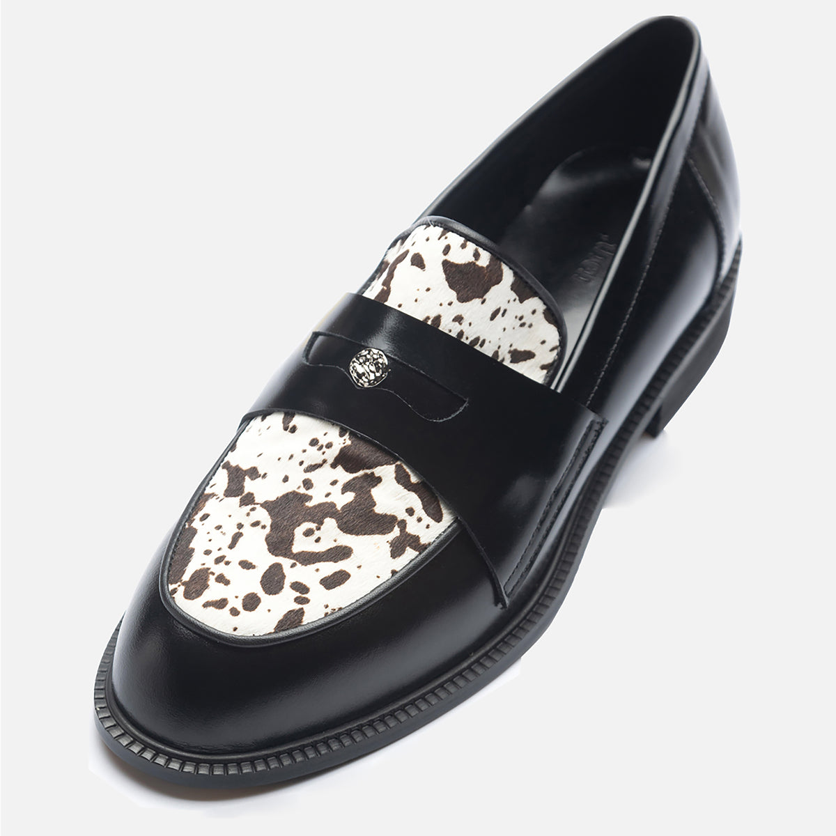 A pair of THEN Black Leather Loafers with Cowhide Print Vamp, handmade in Korea, featuring a decorative metal emblem on the strap, displayed on a white background.