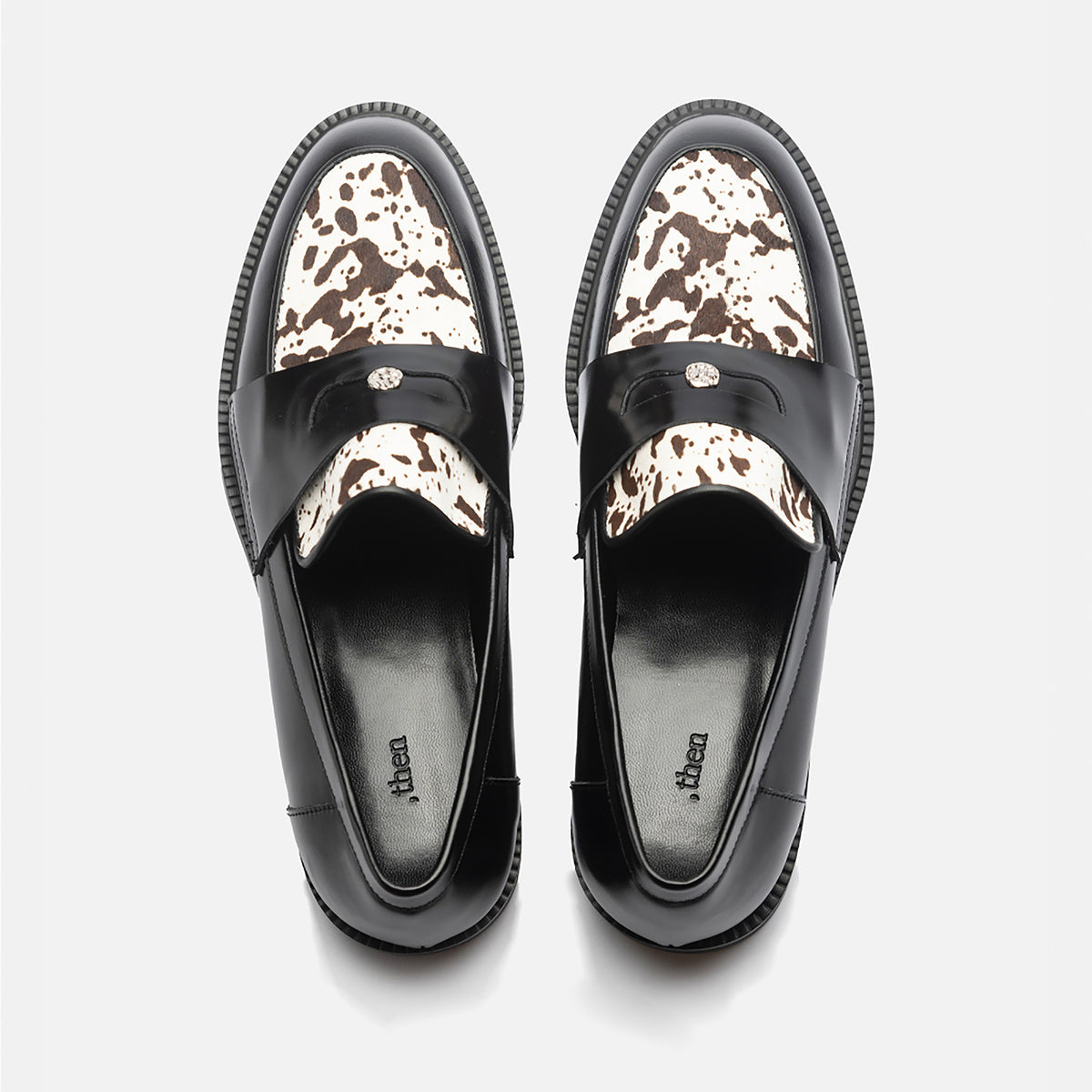 A pair of THEN Black Leather Loafers with Cowhide Print Vamp, handmade in Korea, shown from above on a white background. The black insoles are branded with the word "THEN".