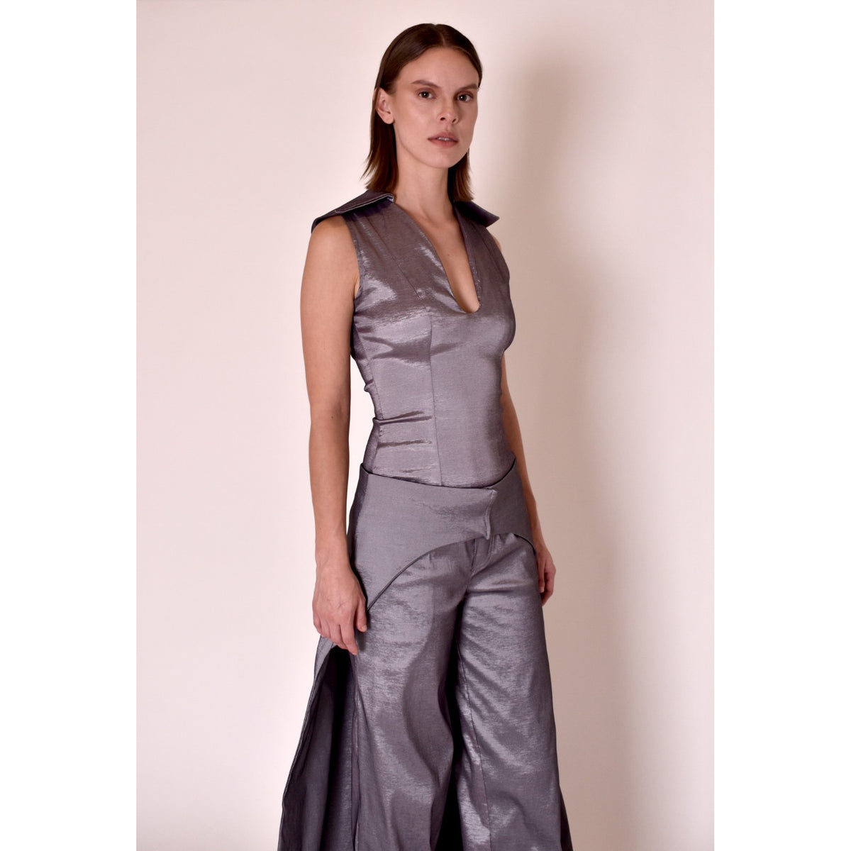 Woman wearing a silver metallic outfit against a plain background