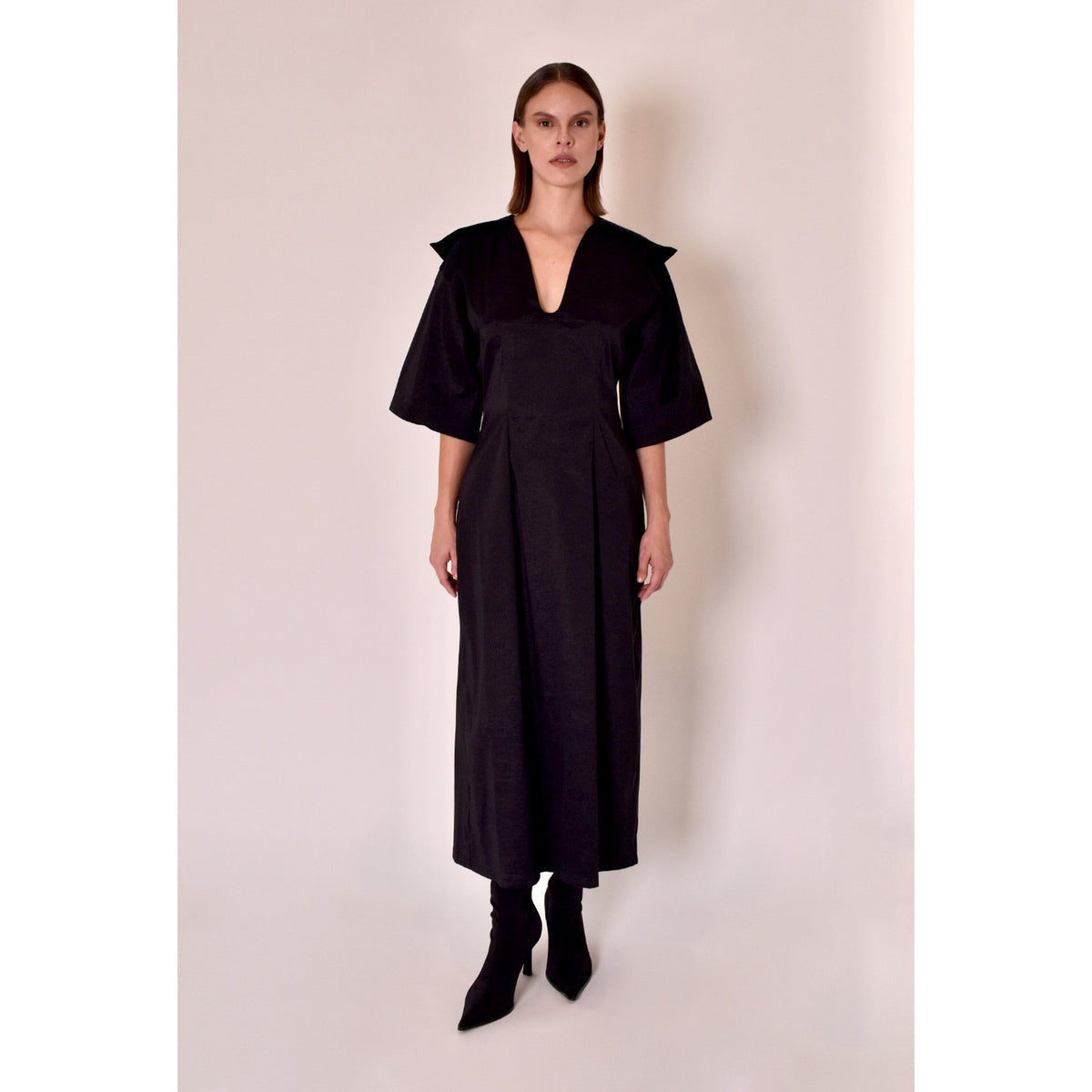 Woman wearing a black dress against a plain background