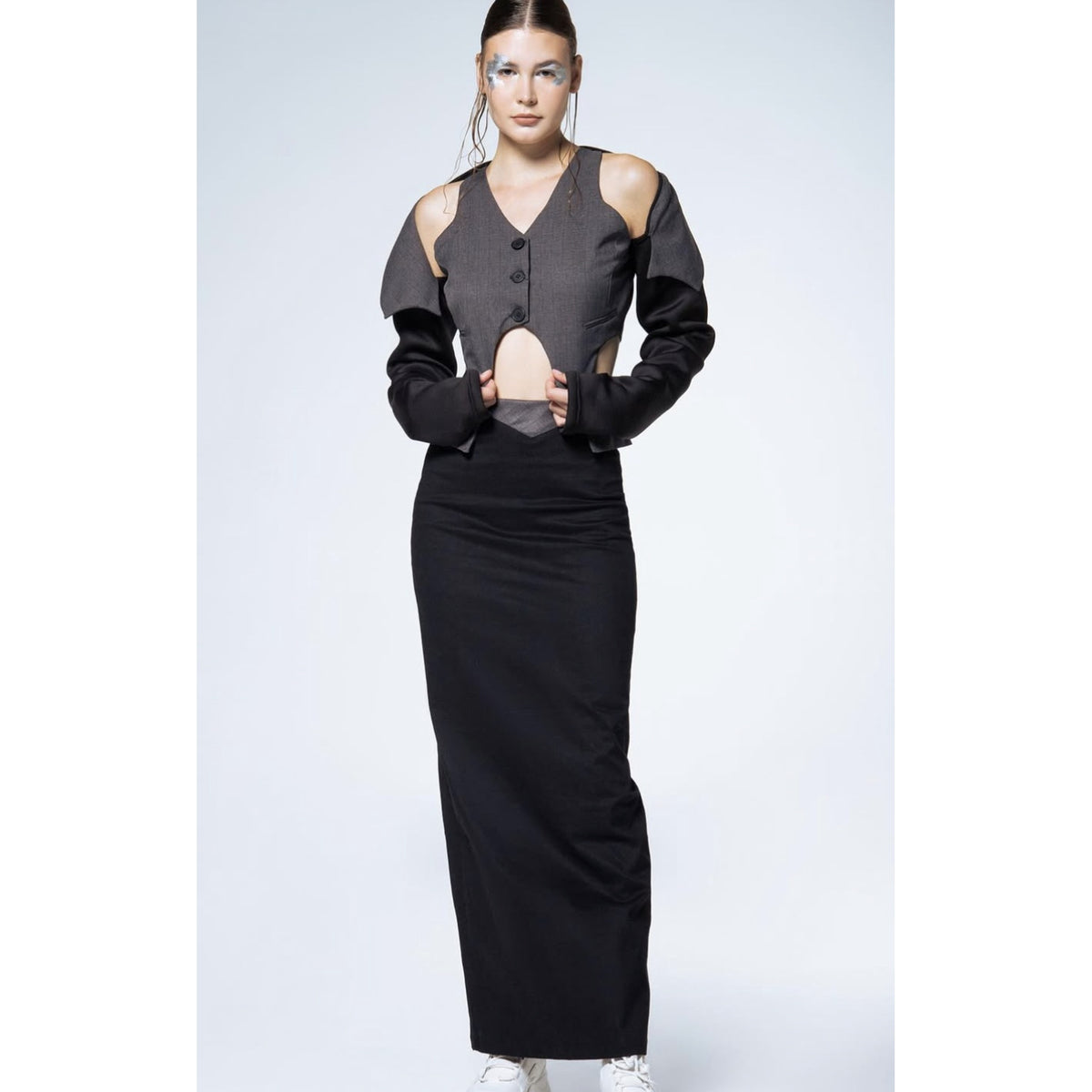 Woman wearing a black top with cut-out shoulders on a white background