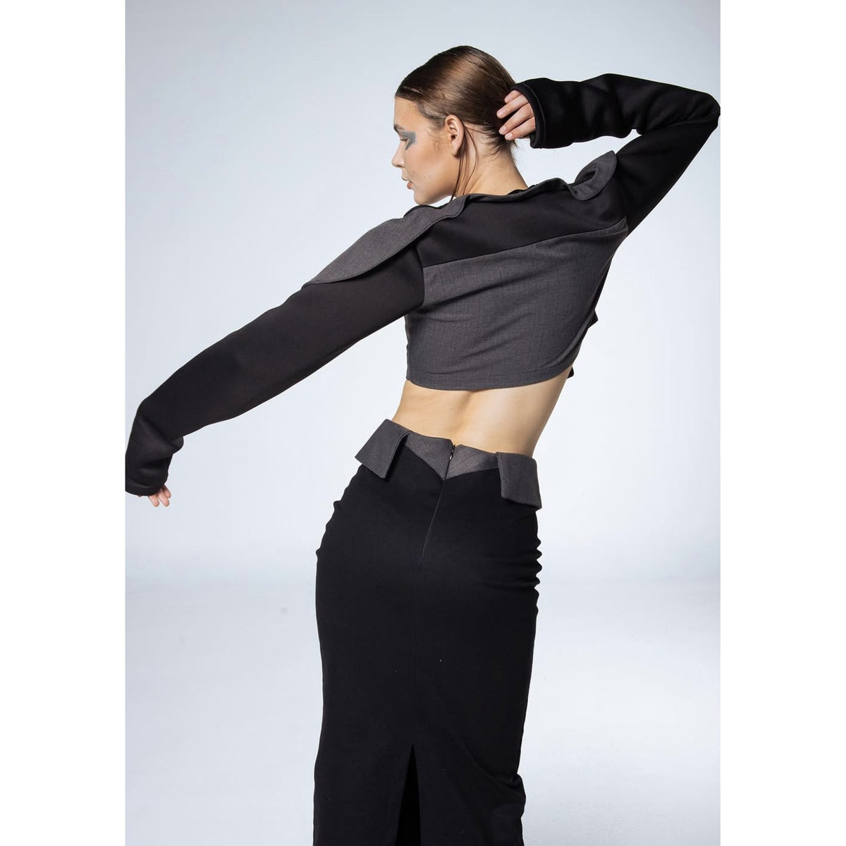 Person wearing a black and gray outfit with a unique design on a white background