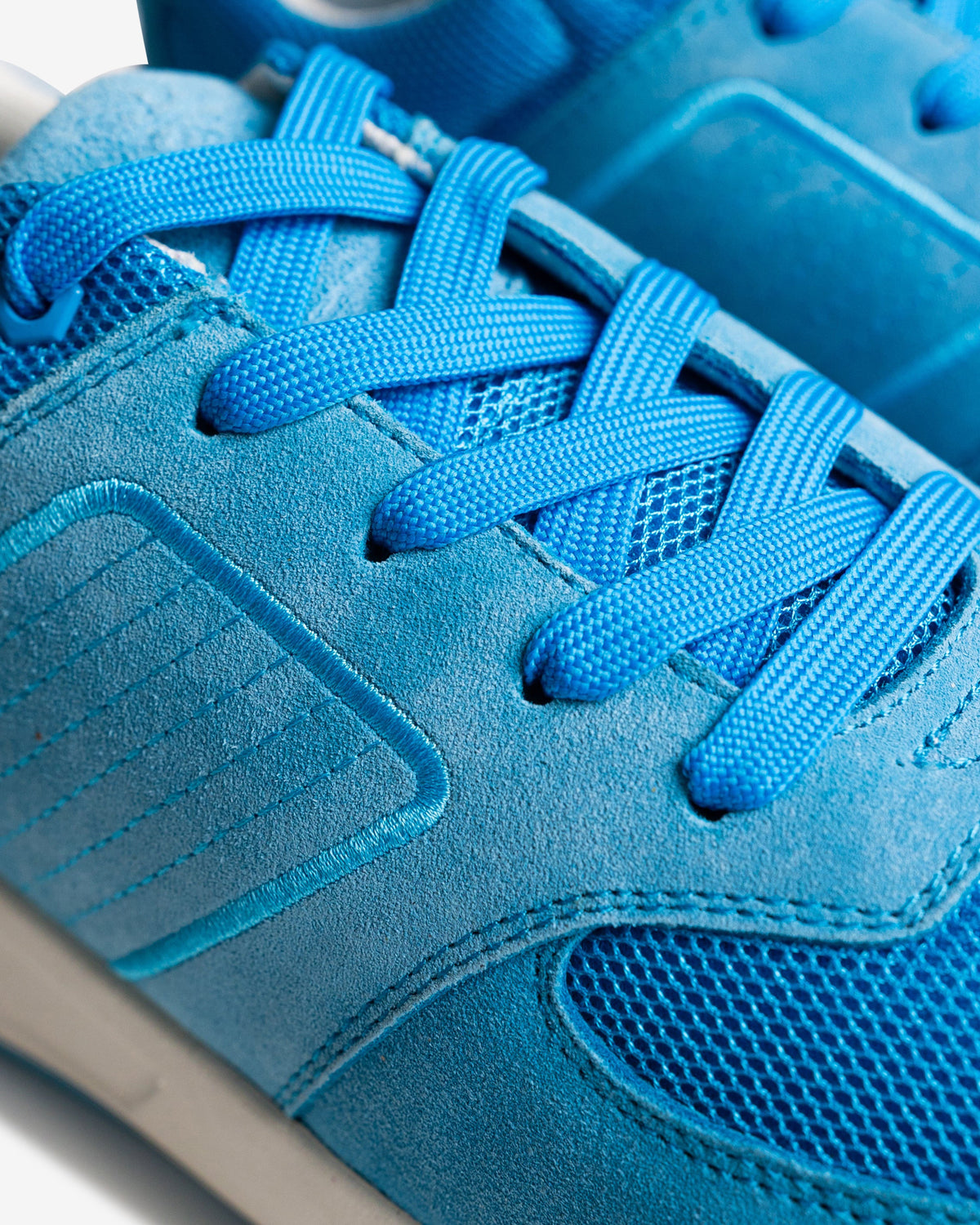 Close-up of a blue sneaker with laces on a white background