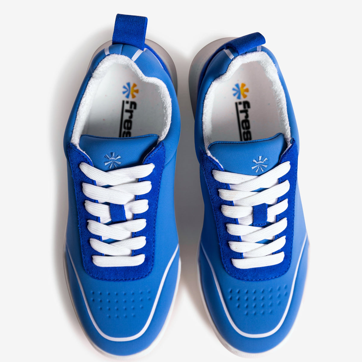 Pair of blue children's shoes with white laces on a light gray background