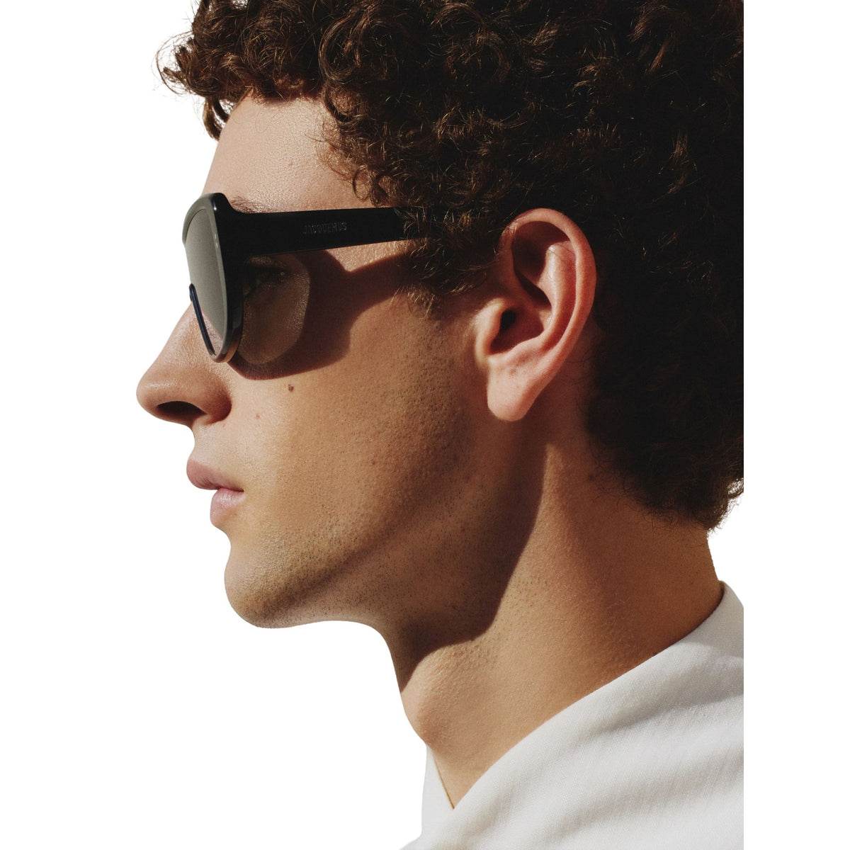 Side profile of a person wearing sunglasses with a white background