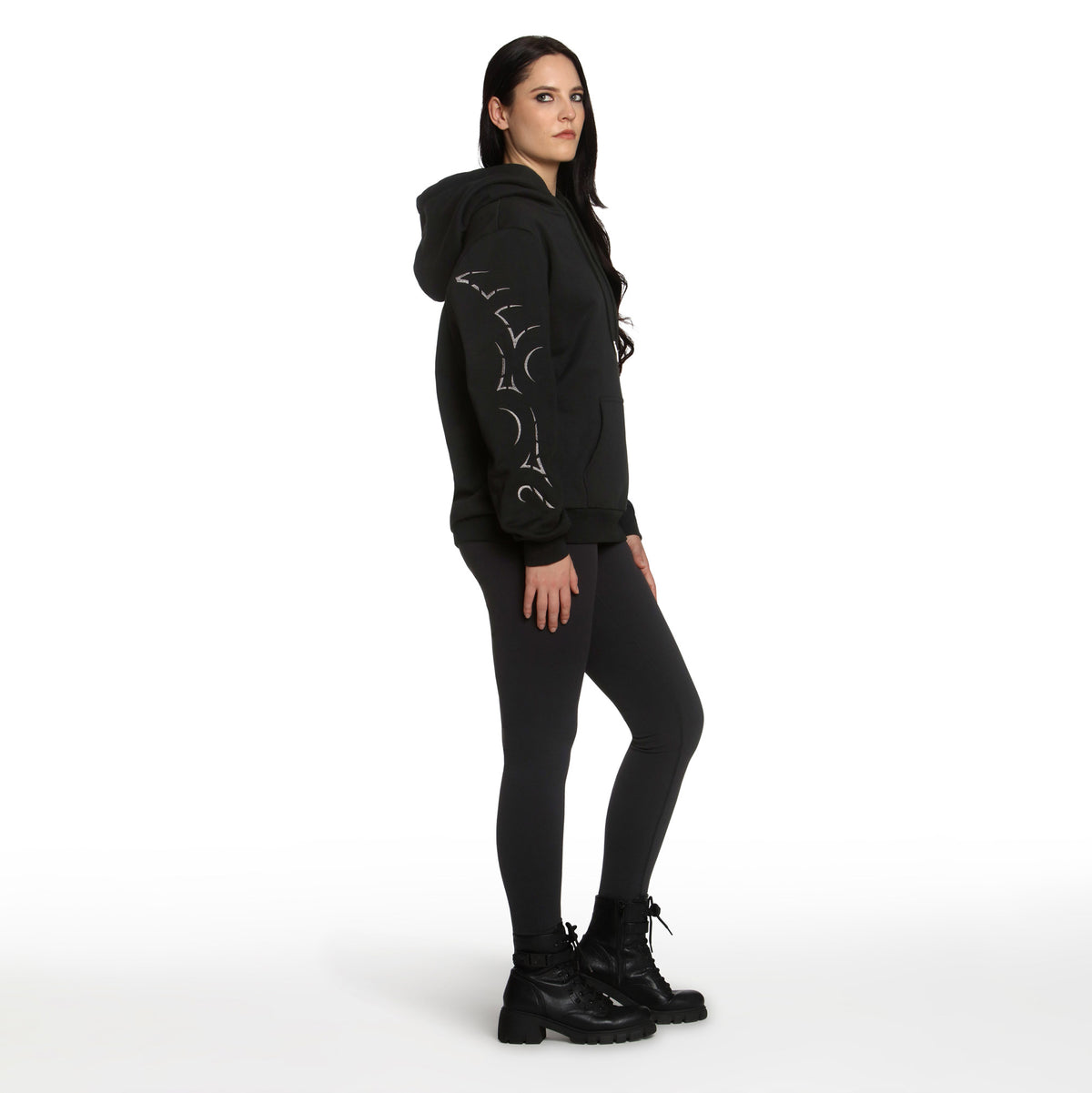 Woman wearing a black hoodie, leggings, and boots on a white background