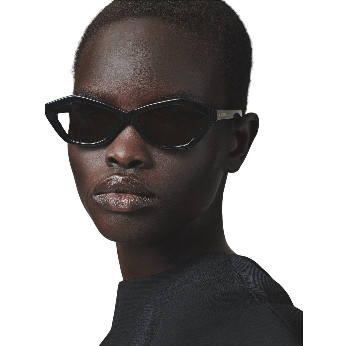Person wearing black cat-eye sunglasses on a white background