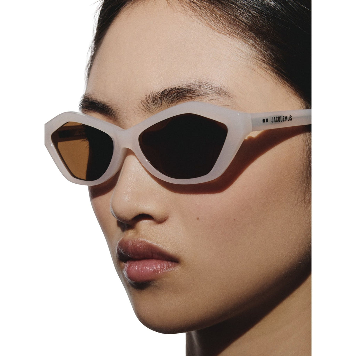 Person wearing a pair of sunglasses with a neutral background