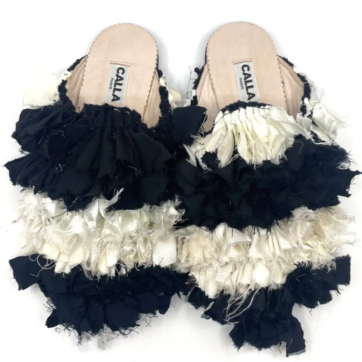 Pair of sandals with black and white ruffled edges on a white background