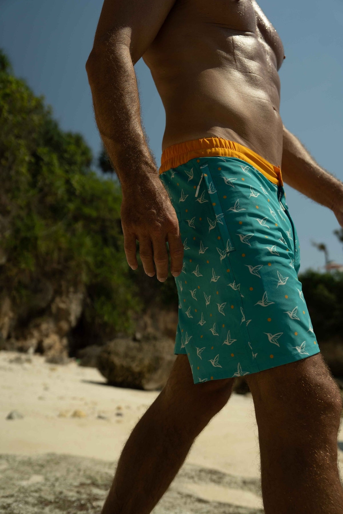 Model wearing Aquamarine monogram swim trunks outdoors