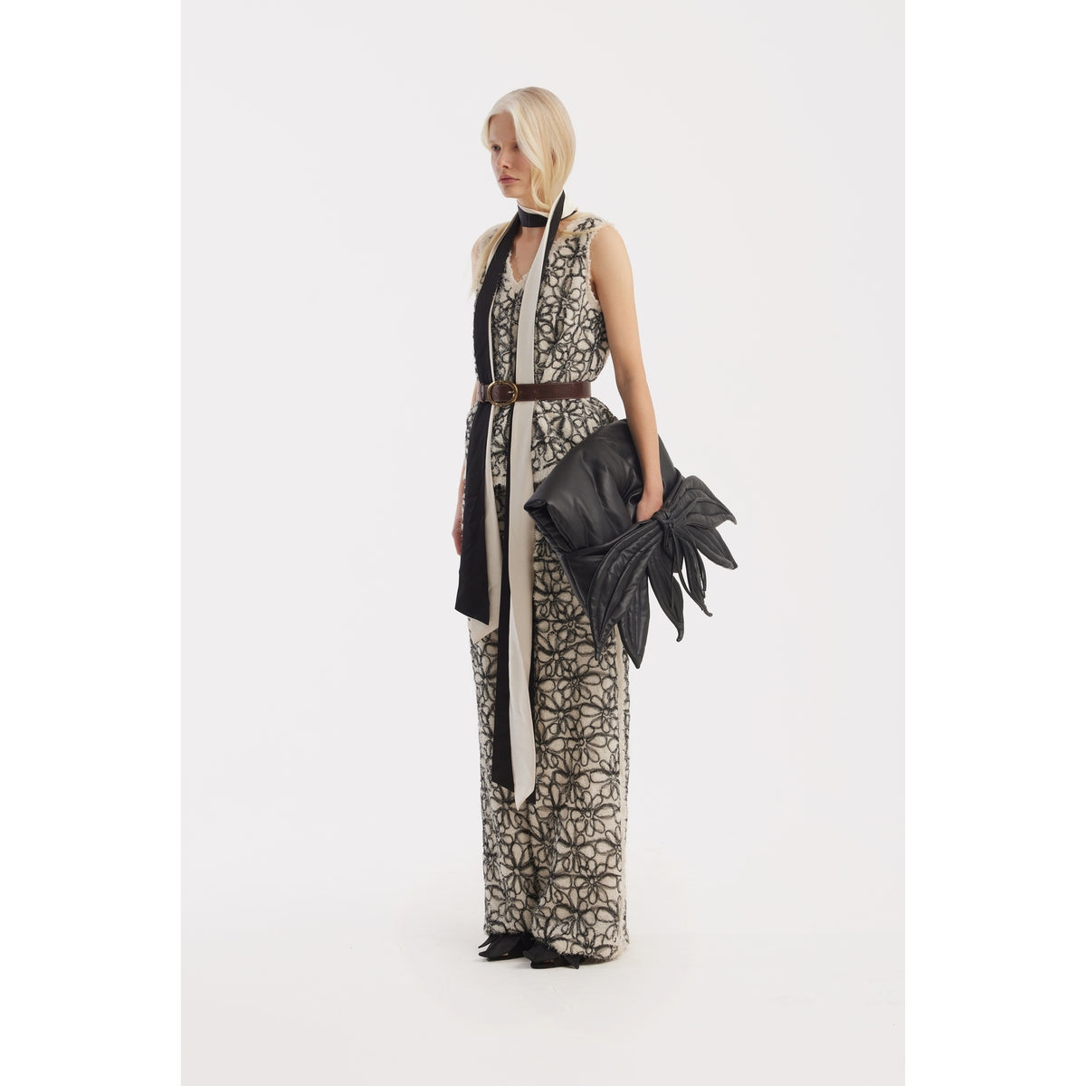 A woman with blonde hair stands against a white background, wearing JULIA ALLERT Elastic Waist Abstract Textured Wide Pants in ivory, paired with a black sculptural handbag, belt, and scarf.