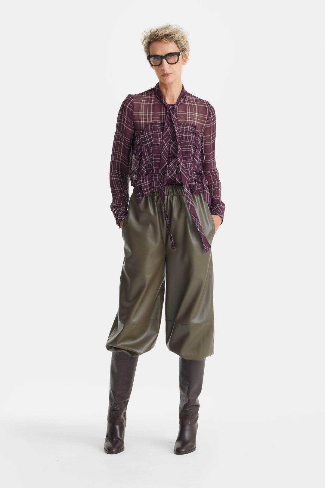 Person wearing a plaid shirt, green pants, and black boots on a white background