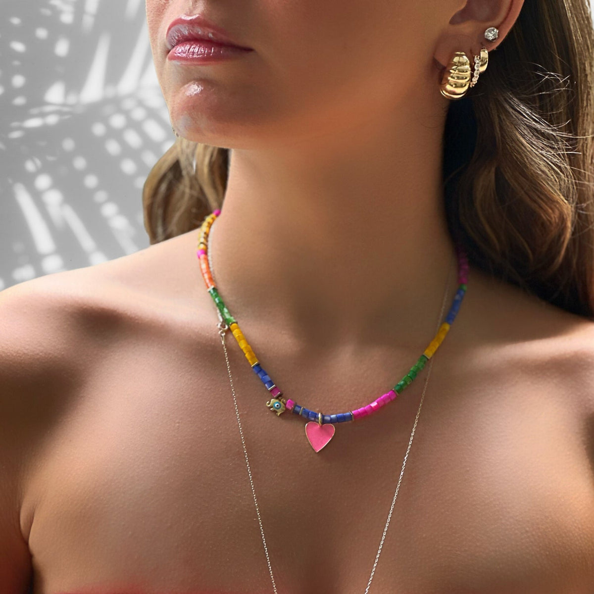 Handmade beaded necklace with a sterling silver elephant charm, pink enamel heart pendant, and gold butterfly charm