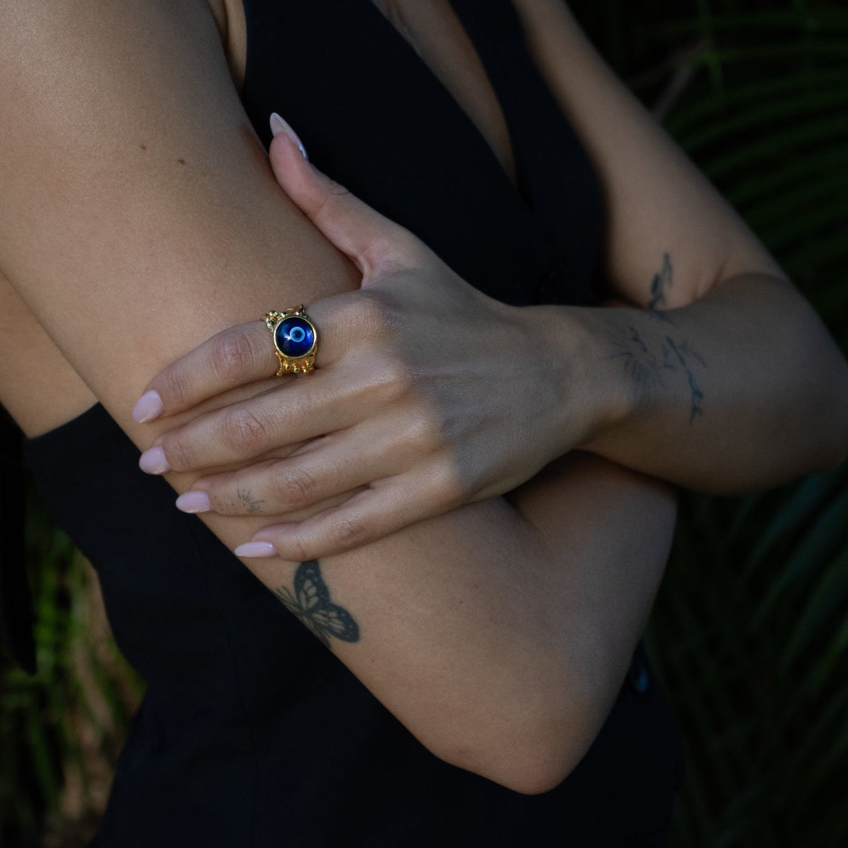 Adjustable 24K gold plated bronze evil eye ring with blue center stone and white enamel accents.