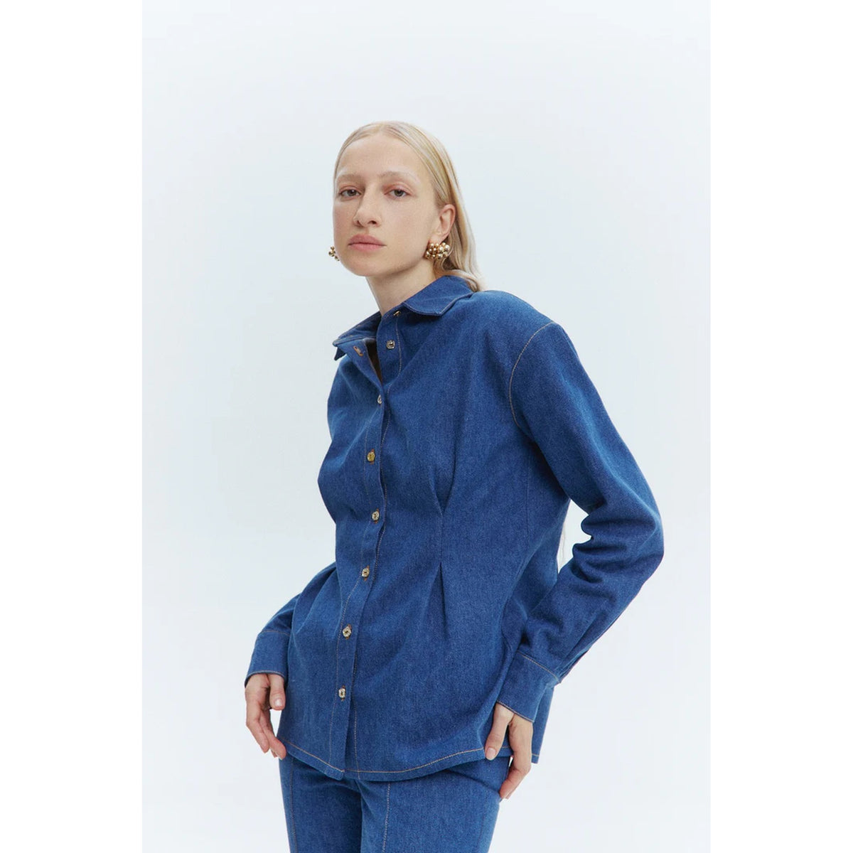 Person wearing a blue denim shirt and pants on a white background