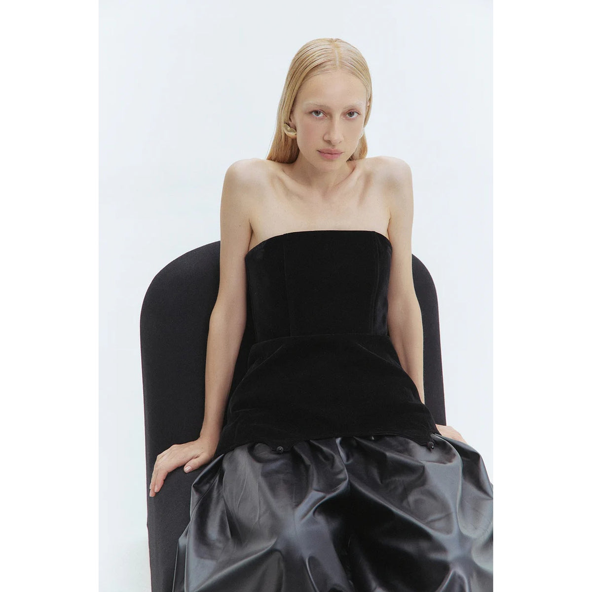 Woman wearing a strapless black top with a white background