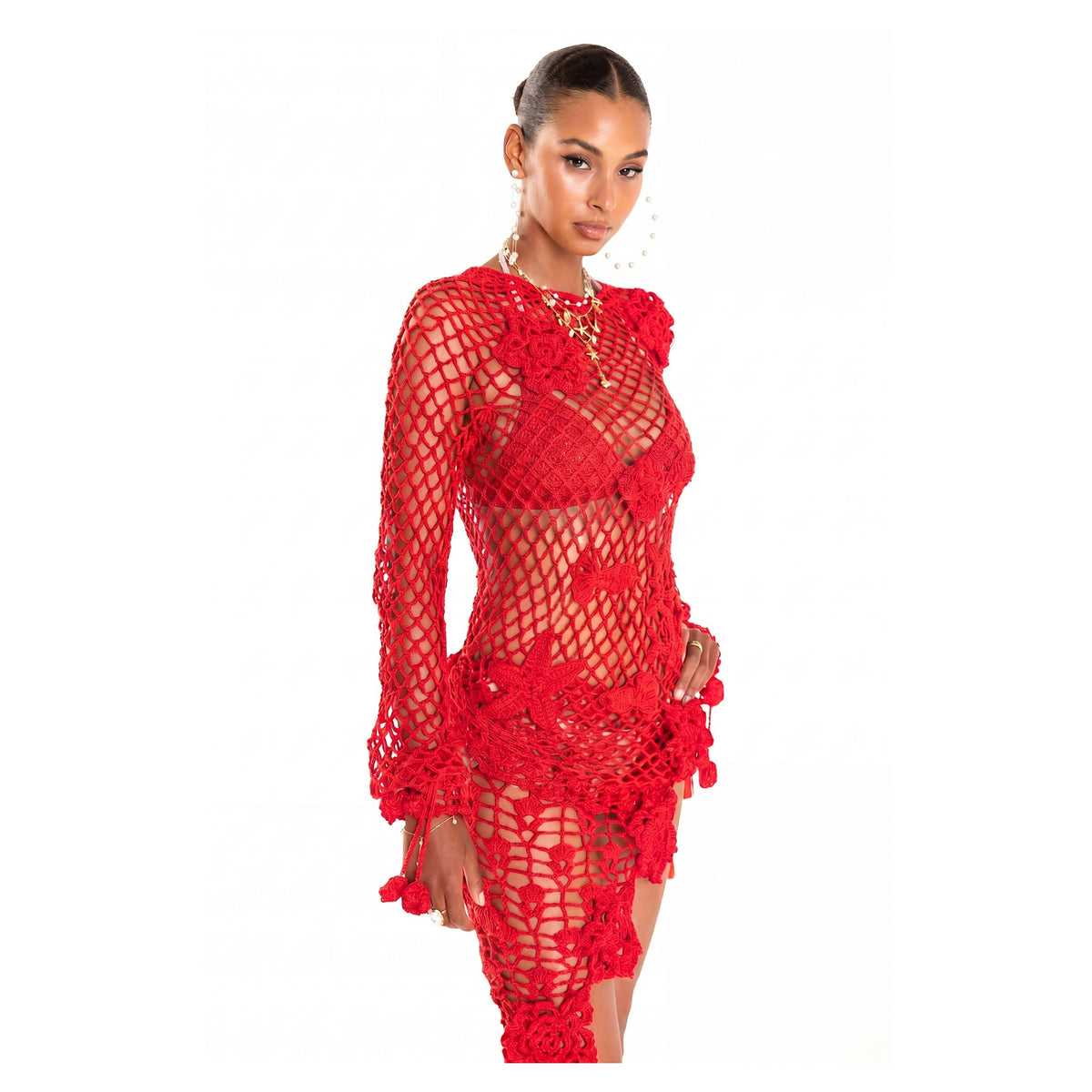 A woman poses confidently in the ANDREEVA Cherry Handmade Crochet Top, featuring bold red floral crochet over a matching bralette and shorts. She completes her look with slicked-back hair and hoop earrings against a plain white background.