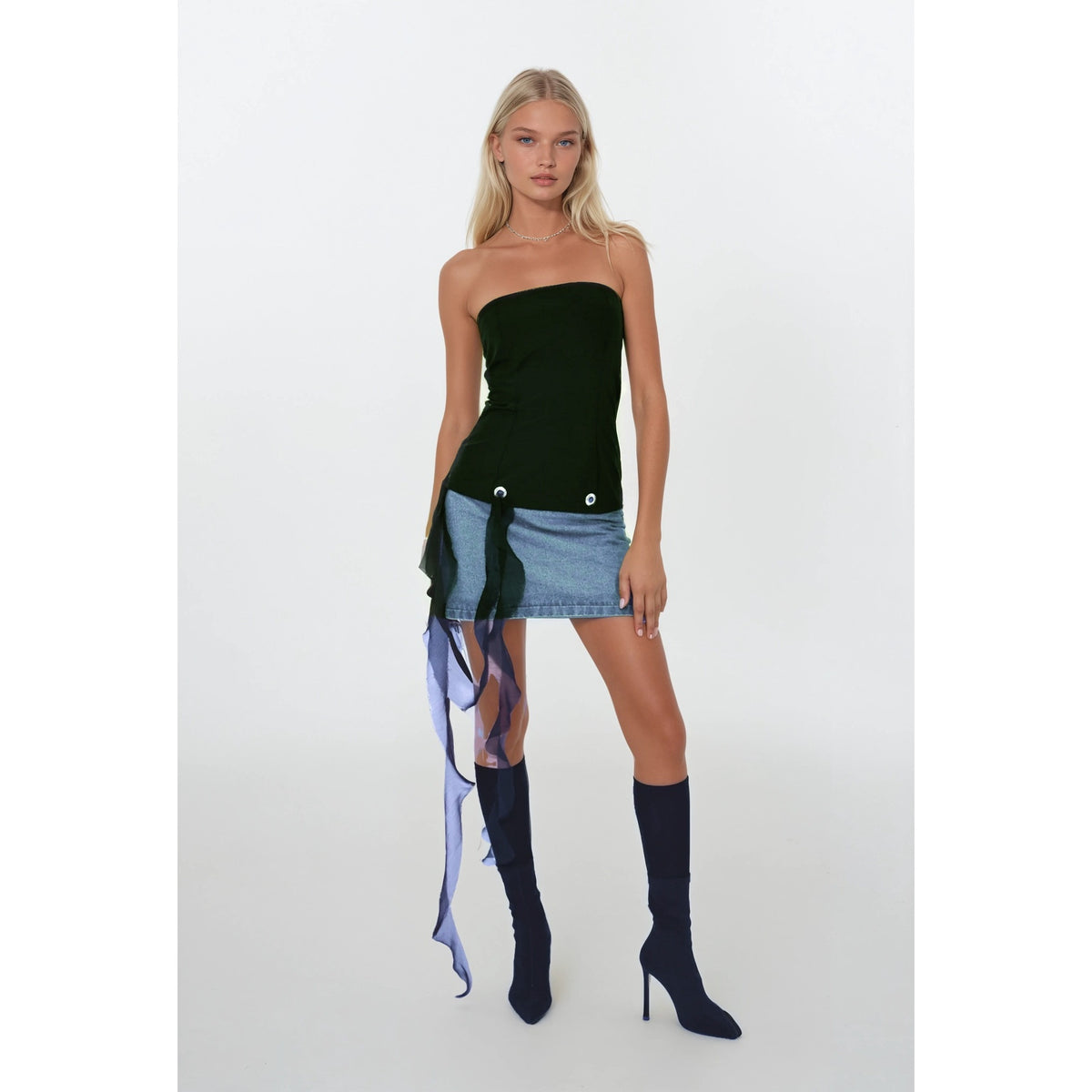 Woman wearing a black strapless top and denim skirt with long, colorful scarf on a white background